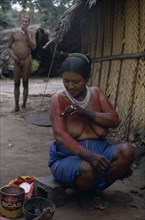 COLOMBIA, North West Amazon, Tukano Indigenous People, Barasana woman Paulina  applying red Achiote