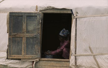 MONGOLIA, Gers Yurts, Khalkha Woman doing chores framed in open doorway of recently erected ger or