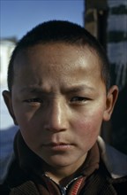 MONGOLIA, Altai town, Head and shoulders portrait of strong young Khalkha boy looking direct to