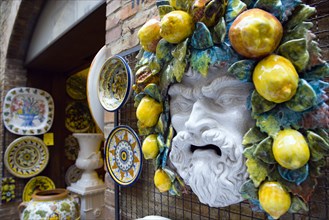 ITALY, Tuscany, San Gimignano, Outdoor shop display of ceramics with colourful plates and the face