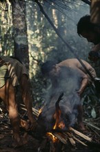 COLOMBIA, North West Amazon, Vaupes, Maku hunters singeing hair from carcass of wild boar over open