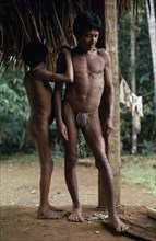 COLOMBIA, North West Amazon, Vaupes, Middle aged Maku nomad standing with his son beside frame of