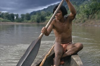 COLOMBIA, Choco, Embera Indigenous People, Embera man using single oar to steer wooden dug out