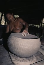 COLOMBIA, Choco, Embera Indigenous People, Embera woman puts final touches to a large clay cooking
