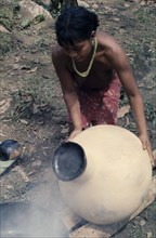 COLOMBIA, Choco, Embera Indigenous People, "Embera woman uses molten beeswax to seal a  cantaro