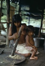 COLOMBIA, Choco, Embera Indigenous People, Embera woman grating Jagua fruit using palm-spine grater