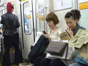 JAPAN, Honshu, Tokyo, "Ginza - three women on a subway train, right side young woman, shopping bags
