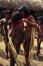BRAZIL, Mato Grosso, Indigenous Park of the Xingu, Young Panara women applying red and black body