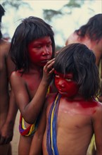 BRAZIL, Mato Grosso, Indigenous Park of the Xingu, Young Panara girls applying red karajuru face