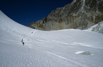 NEPAL, Everest Trek, Near Dzongla, Trekkers desending through snow from the Cho La towards Dzongla