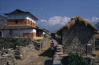 NEPAL, Dhorpatan Trek, Dhorpatan, Woman walking between stone houses in Dharapani Village and the