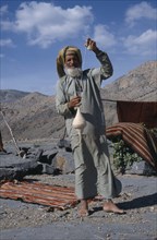 UAE, Oman, Jabal Shams, Elderly man using spindle to spin thread for rug making.