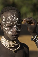 ETHIOPIA, Lower Omo Valley, Mago National Park, Karo woman painting her daughters face