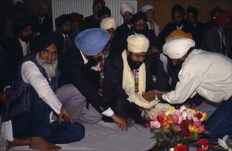 ENGLAND, Religion, Sikhism, Groom receiving gifts from guests during wedding ceremony.