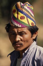 NEPAL, East, Chainpur, Head and shoulders portrait of a man wearing a Topi  traditional hat near