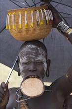 ETHIOPIA, South Omo Valley, Mursi Tribe, Woman with lip plate holding umbrella to shelter from sun