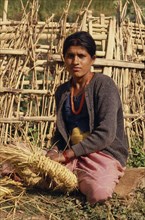 NEPAL, East, Near Chainpur, Portrait of woman with a nose piercing sat on the ground weaving in