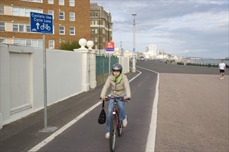 ENGLAND, East Sussex, Brighton, Cyclist on seafront cycle lane in hove.