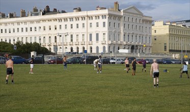 ENGLAND, East Sussex, Brighton, People playin football on hove seafront lawns.