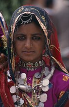 INDIA, Rajasthan, Bikaner, Portrait of a young tribal woman wearing traditional dress and jewellery
