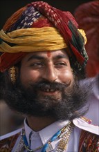 INDIA, Rajasthan, Bikaner, Head and shoulders portrait of a Rajput man smiling with a beard wearing