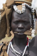 ETHIOPIA, South Omo Valley, Mursi Tribe, Portrait of woman with feather in her mouth.