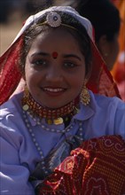 INDIA, Rajasthan, Jhunjhunu, Portrait of a young girl dancer smiling wearing traditional dress and