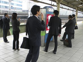 JAPAN, Honshu, Tokyo, "Yurakucho - the smokers corner on the JR train platform, men and young woman