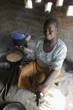 GAMBIA, Western Gambia, Tanji, "Tanji Village.  Smiling woman cooking traditional dish of groundnut