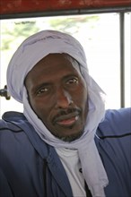 GAMBIA, Atlantic Coast, Banjul, Head and shoulders portrait of African Muslim man travelling on a