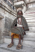 INDIA, Rajasthan, Udaipur, Elderly male Hindu beggar sitting on steps outside the Jagdish Temple
