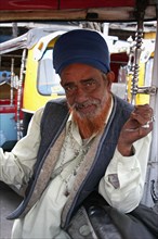 INDIA, Delhi, New Delhi, "Portrait of auto rickshaw driver inside vehicle with red dyed beard,