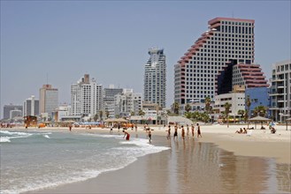 ISRAEL, Tel Aviv, "Beach with people sunbathing and at waters edge overlooked by high rise, modern