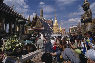 THAILAND, Bangkok, Crowds making offerings of incense and lotus flower buds at shrine in the Royal