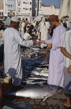 UAE, Oman, Muscat, Mutrah fish market.  Male vendor and customer making cash transaction over