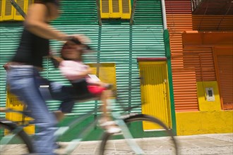 ARGENTINA, Buenos Aires, Cyclist passing colourful houses in La Boca.