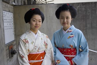 JAPAN, Honshu, Kyoto, "Two Maiko apprentice Geisha wearing patterned kimono, standing outside their