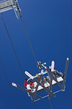 20091059 View cable ski lift chair against blue sky with clouds. American North America United States America White  WeatherTravelTransportDominant RedDominant WhiteDominant BlueRegion - North A...