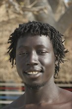GAMBIA, Western Gambia, Tanji, Tanji coast.  Head and shoulders portrait of smiling young African