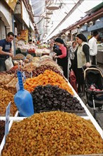 ISRAEL, Jerusalem, "Women with baby in pram making purchase at stall selling dried fruit and nuts
