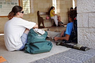 ISRAEL, Hazafon, Galilee, Young Israeli students sitting outside a Christian church with gun lying