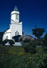IRELAND, County Kerry, Sneem, Exterior of white church building with wild flowers and flowering