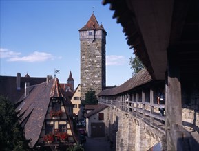 GERMANY, Bavaria, Rothenburg, View from the town walls under covered walkway toward tower and gable