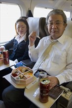 JAPAN, Honshu, Shinkansen train series 700 known as the ‘bullet train’.  Japanese couple eating