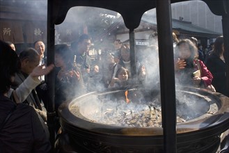 JAPAN, Honshu, Tokyo, Asakusa Kannon or Senso-ji Temple.  Japanese people wafting smoke from