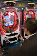 JAPAN, Honshu, Tokyo, Shinjuku.  Japanese man gambling at electronic machine