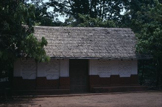 GHANA, Ashanti, Traditional thatched house with intricate patterns on walls.