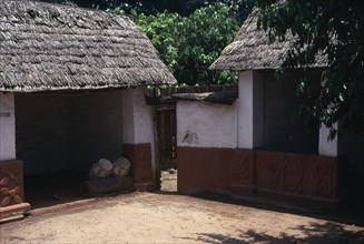 GHANA, Ashanti, Traditional thatched house with intricate patterns on walls. Ceremonial drums