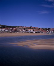 SPAIN, Cantabria, San Vicente de la Barquera, Town buildings extending to sea wall with moored
