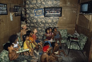 ECUADOR, Guayas Province, Guayaquil , Titus and Nathaniel Moser sitting with children watching